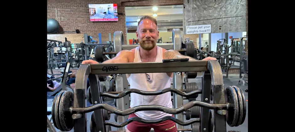 man sitting in front of a barbell rack
