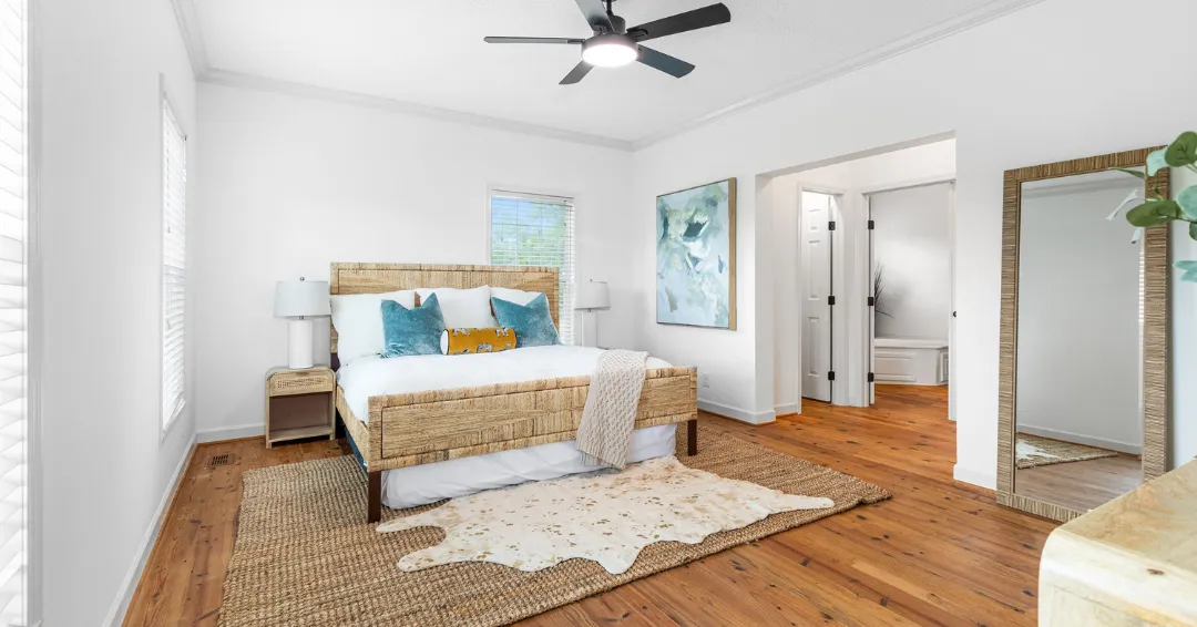 Staged modern bedroom with white walls, woven bed frame, hardwood flooring, and accent decor in Oklahoma home