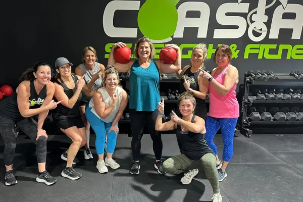 Group of smiling Coastal Strength & Fitness members posing together after a workout at the Newport News gym, celebrating consistency and community for adults over 40