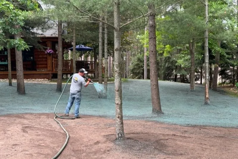 Landworks employee spraying hydroseeds on a client's lawn