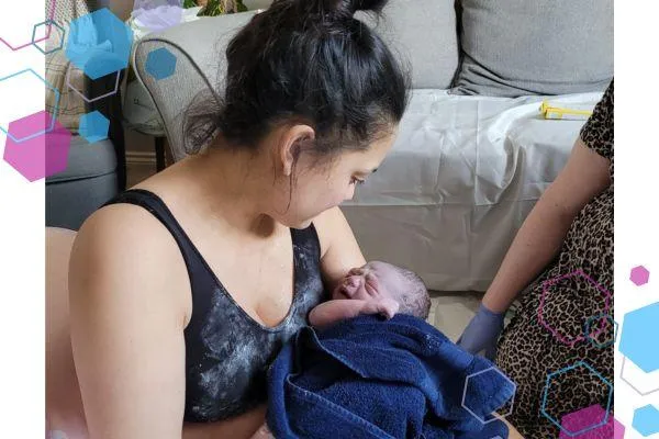 Suzy sitting on the floor cradling her newborn son after a fast home birth in Welwyn Garden City