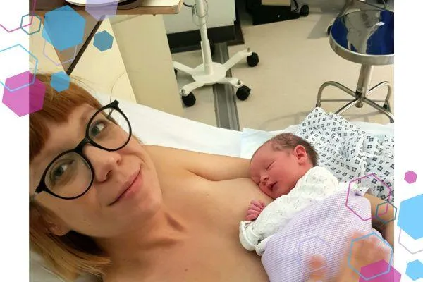 Gemma, a woman with hypermobility syndrome lying in a hospital bed smiling at the camera with her newborn daughter in her arms.