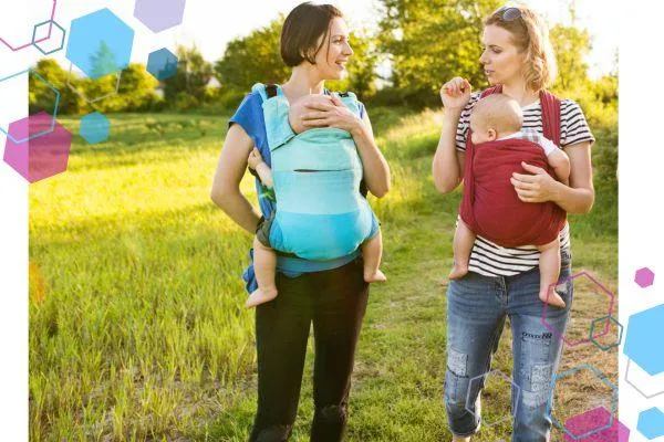 CubCare blog post front cover. Two mums are looking at each other and talking, they are both babywearing their babies in summer. Everyone is dressed in light layers and short sleeves to keep cool whilst babywearing.