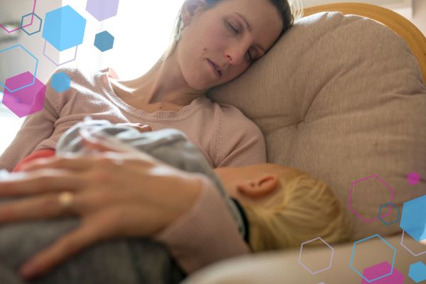 Pregnant person resting on a sofa while holding a sleeping toddler, capturing the exhaustion, divided attention and quiet intensity of early pregnancy the second time around.