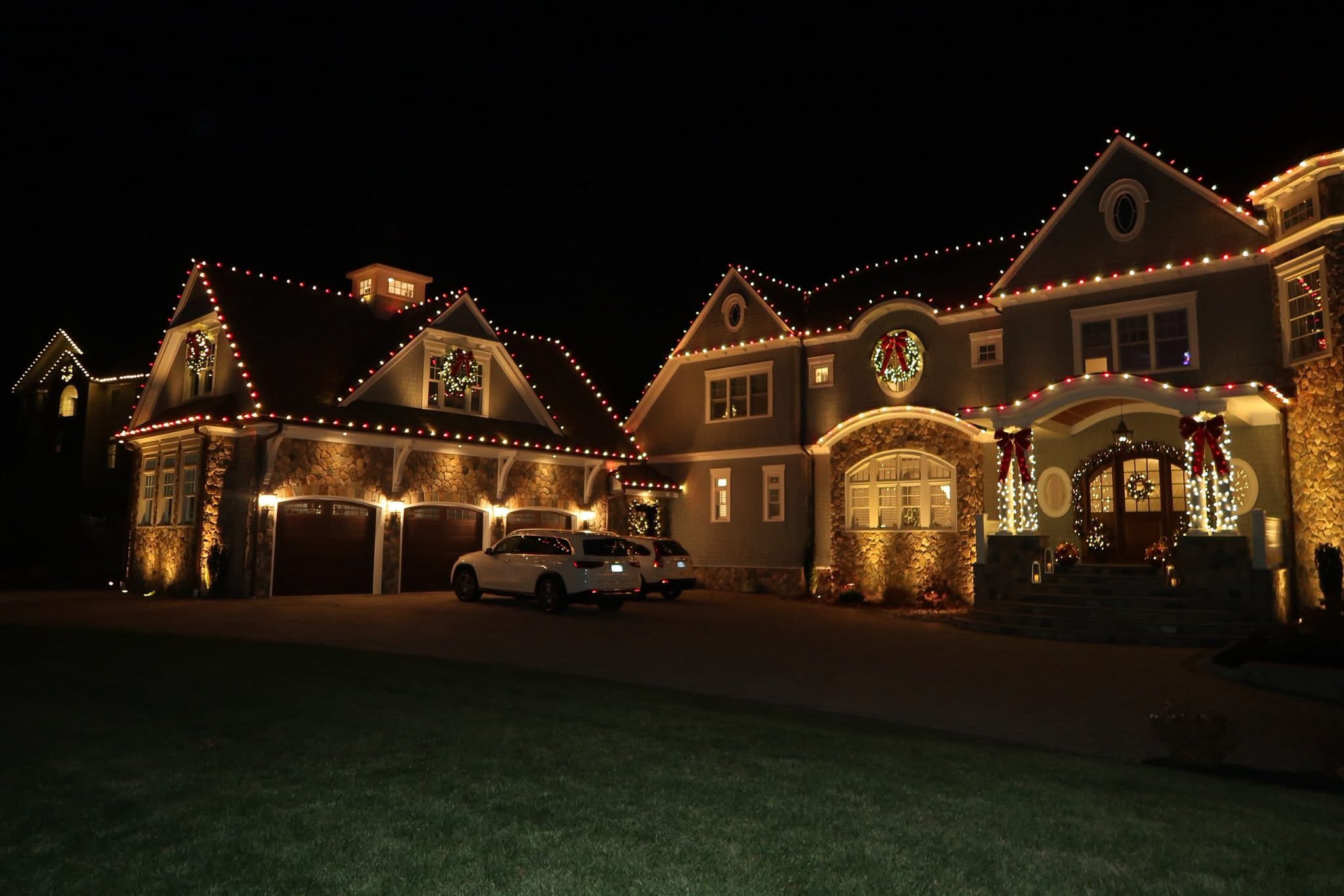 Austin two-story home fully decorated with roofline, trees, and yard Christmas lights professionally installed by Olive & Oak Landscaping.