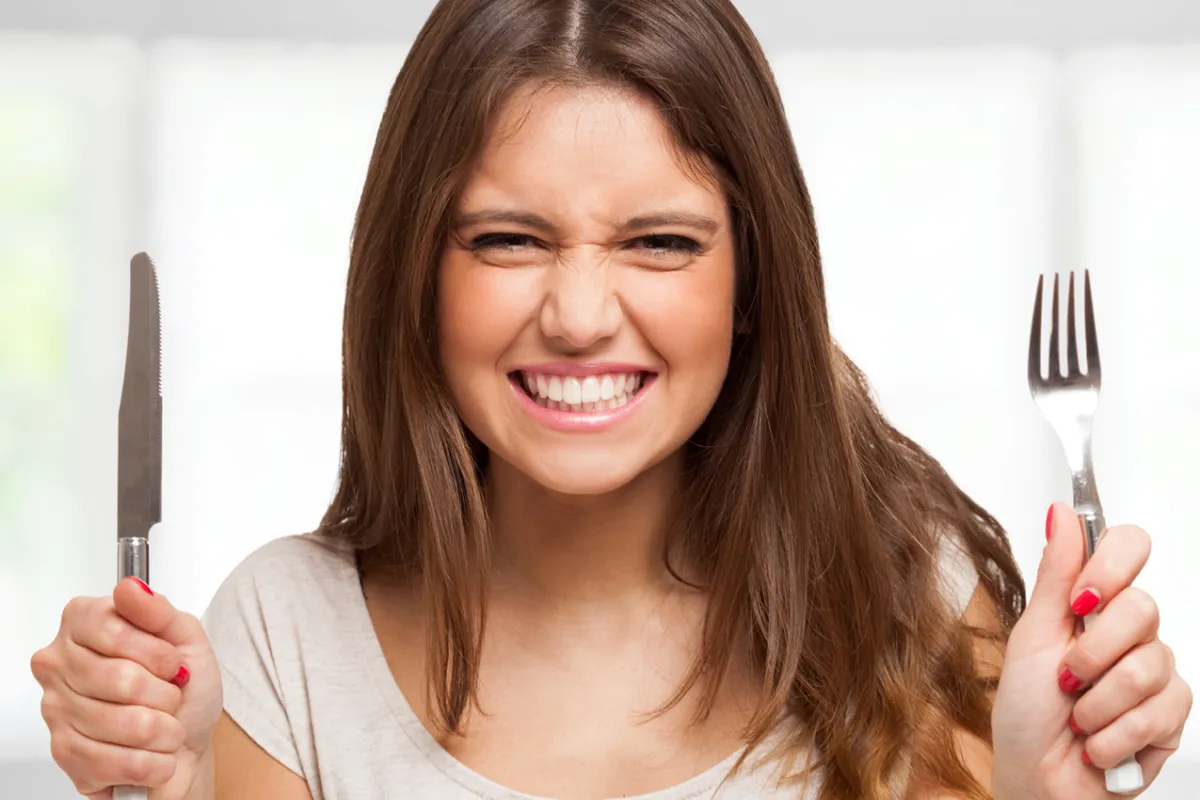 Hungry woman with a knife and fork.