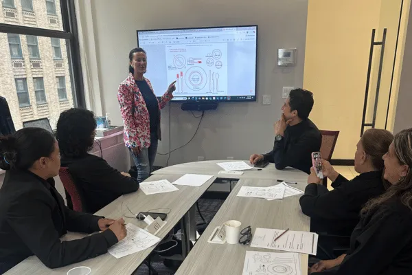 Francesca leading an FS Event Staffing training session, standing at the front of the room with team members seated and engaged in learning