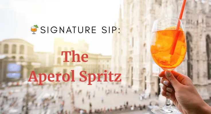 Hand holding a classic Aperol Spritz with orange slice and straw in front of the Milan Cathedral, capturing the authentic Italian aperitivo experience.