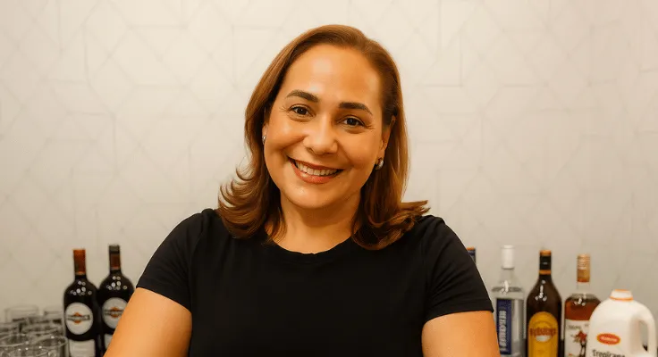 Jamily Vega, FS Event Staffing server, smiling behind a bar with bottles in the background