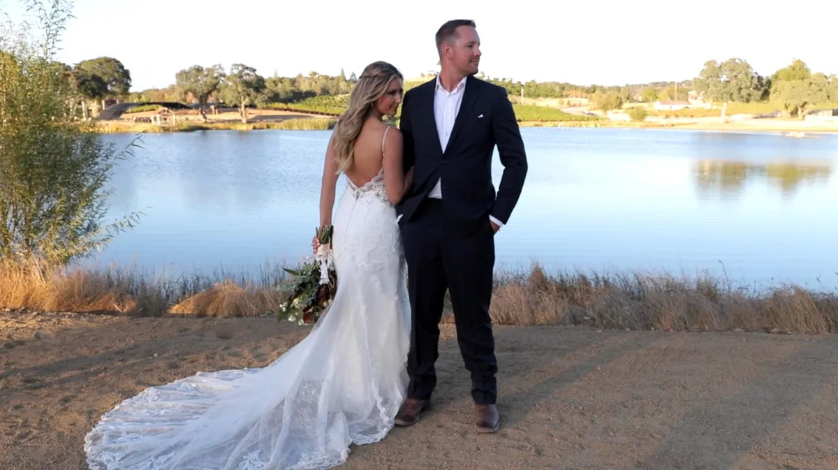 Bride And Groom Standing by a lake during sunset