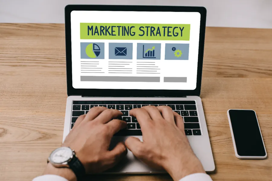 Person typing on a laptop with Marketing Strategy on the screen