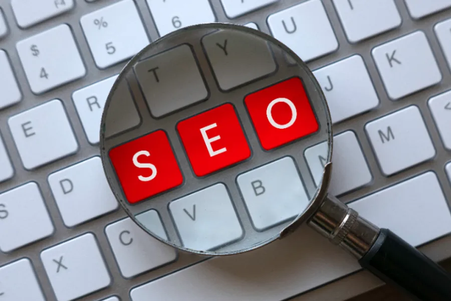 Magnifying glass over a keyboard showing SEO keys