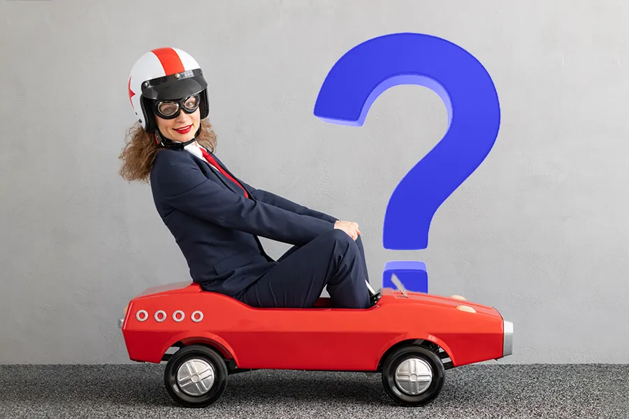 FAQs that drive traffic depiction of a businesswoman in a suite driving a small red car with a large blue question mark behind it