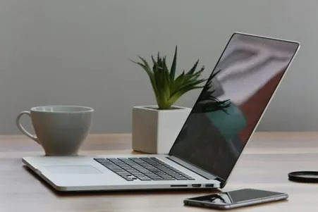 Silver laptop on a table with a white cup
