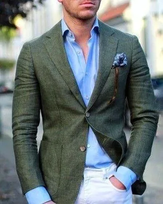 A man wearing a deep green suit jacket, tan dress pants and a light blue dress shirt.