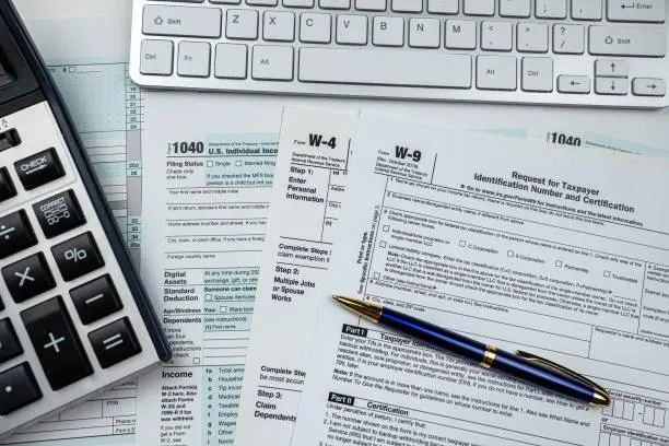 Payroll tax forms and employee pay stubs on a desk