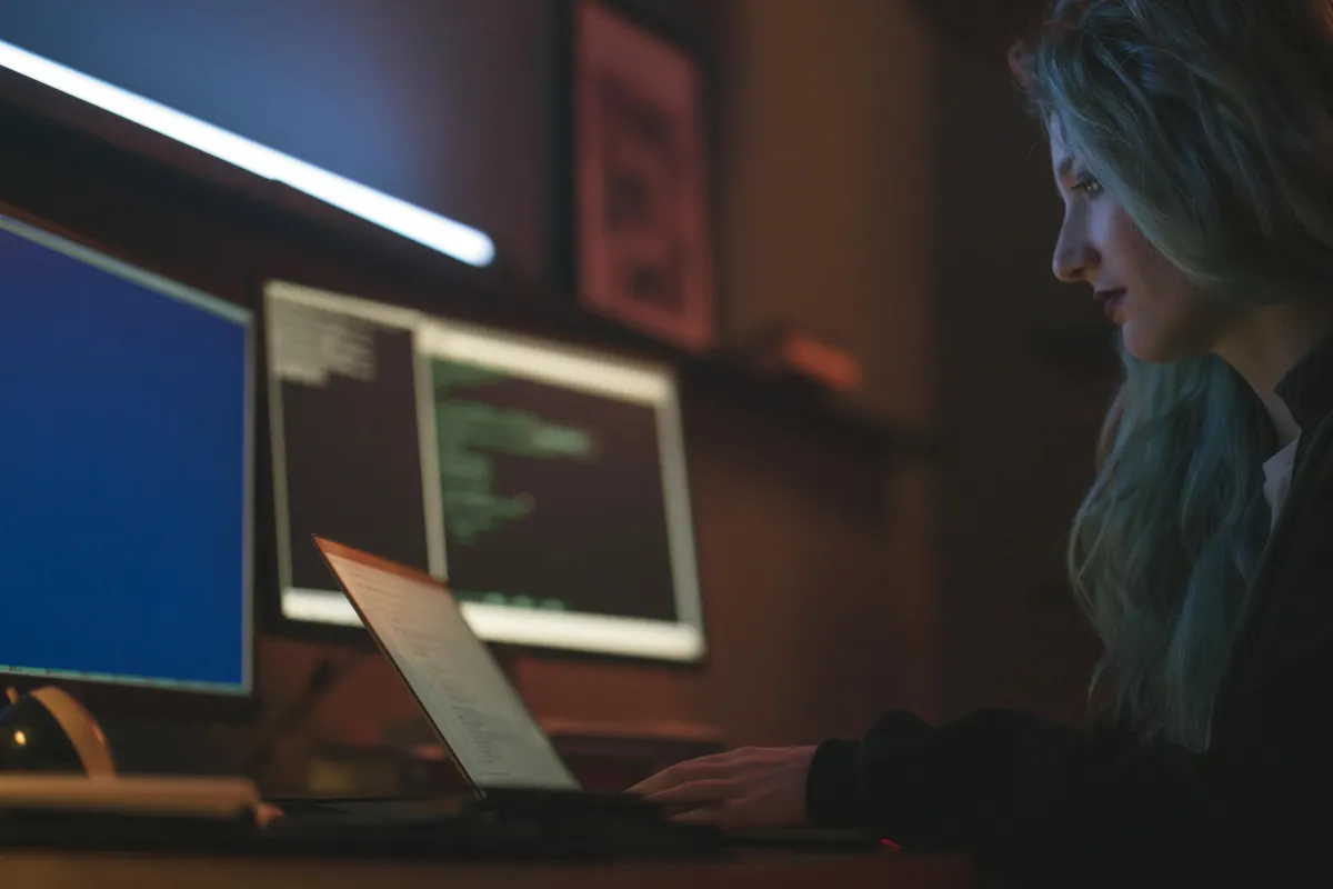 A woman sitting in the dark looking at her computer.