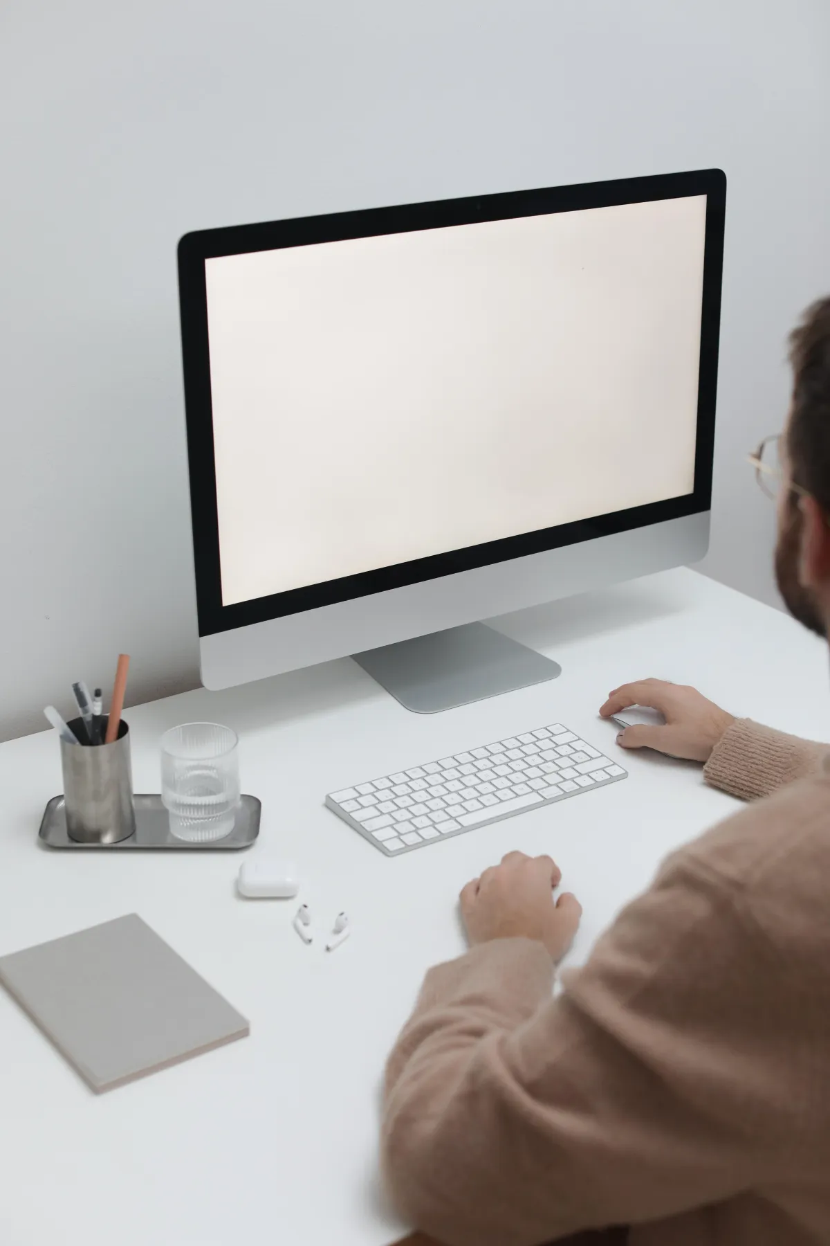 Man using a computer on a white desk.