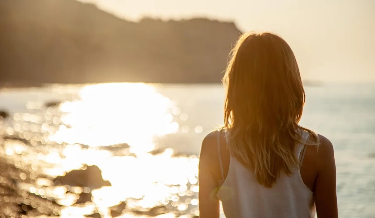 Woman in front of the ocean contemplating about life, discovering meaning and fulfillment