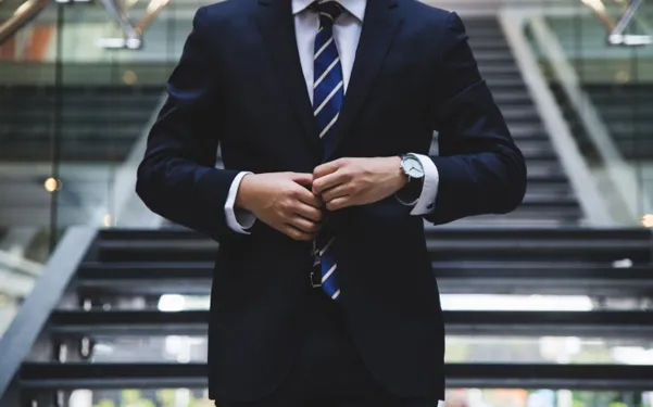 Confident professional adjusting his suit jacket, symbolizing empowerment, change, and breaking free from unfulfilling corporate work
