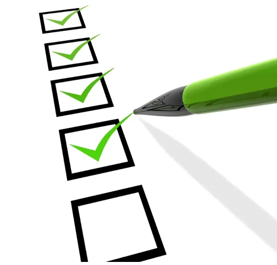Checklist with green check marks and pen, representing completed tasks and goal setting.