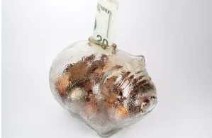 Transparent piggy bank with coins and cash, representing money mindset and financial clarity for coaches.