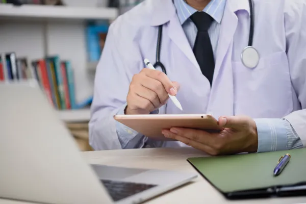 A healthcare professional reviewing encrypted digital records on a tablet, representing secure and compliant patient data management through automation.