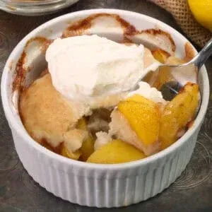 Peach cobbler in a ramekin with vanilla ice cream on top