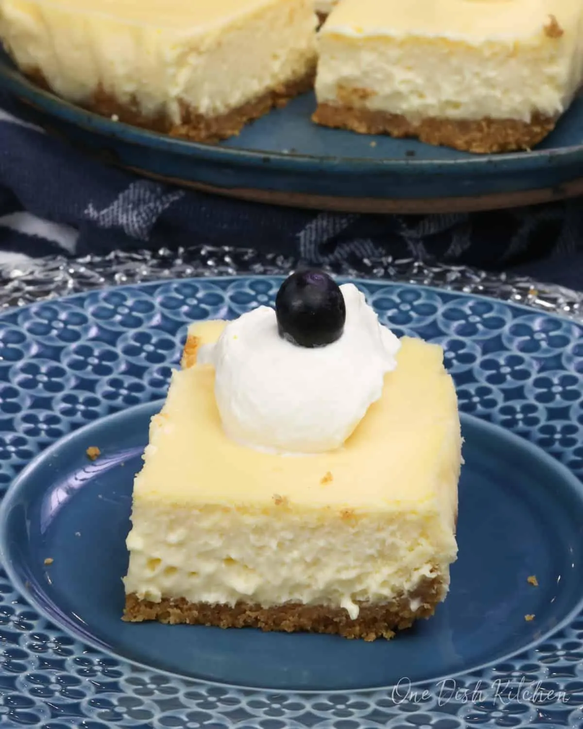 A slice of cheesecake with a flaky crust and a dollop of whipped cream on top