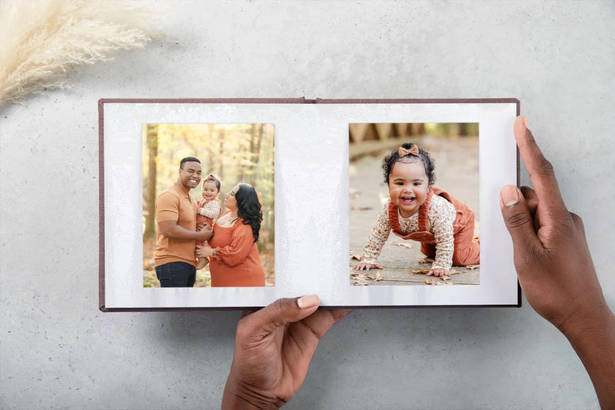 A photo album featuring a family photo on one page and a crawling toddler on another. The family is dressed in oranges for their fall session.