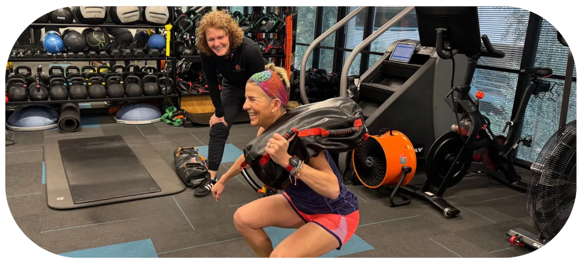 Adult over 40 working with a personal trainer at Quinntessential Fitness, focusing on balanced strength and mobility training in a supportive environment.