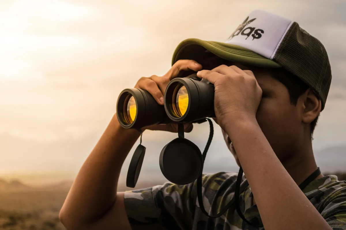 Man in hat looking through binoculars