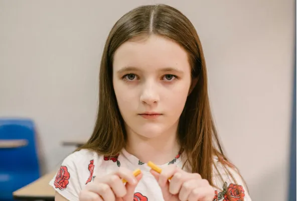 Girl in classroom breaking a pencil