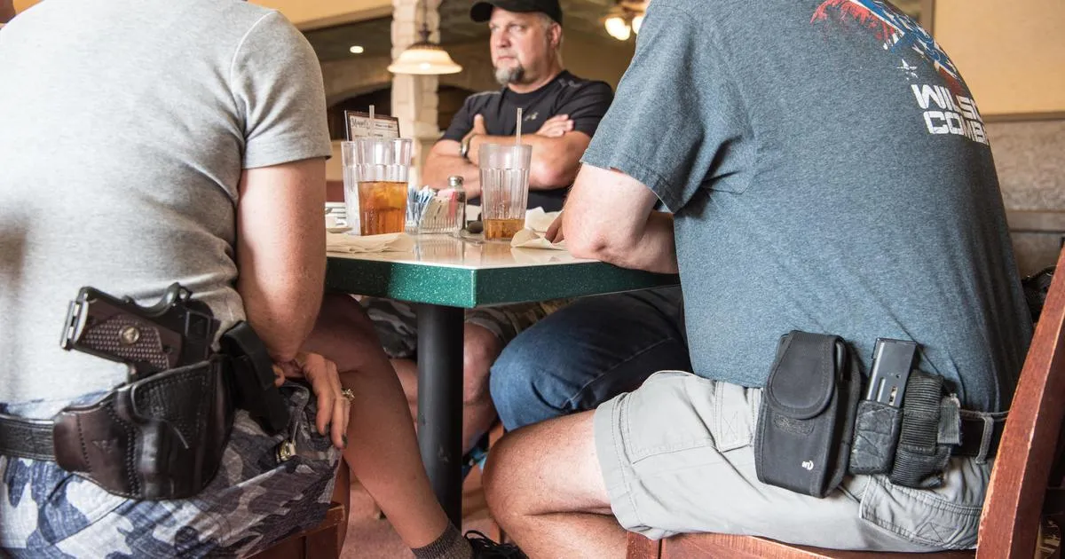 3 men sitting at a table with their firearms on their waist in open carry