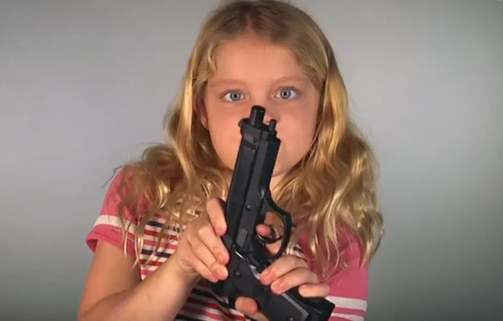 a blond young girl holding a firearm