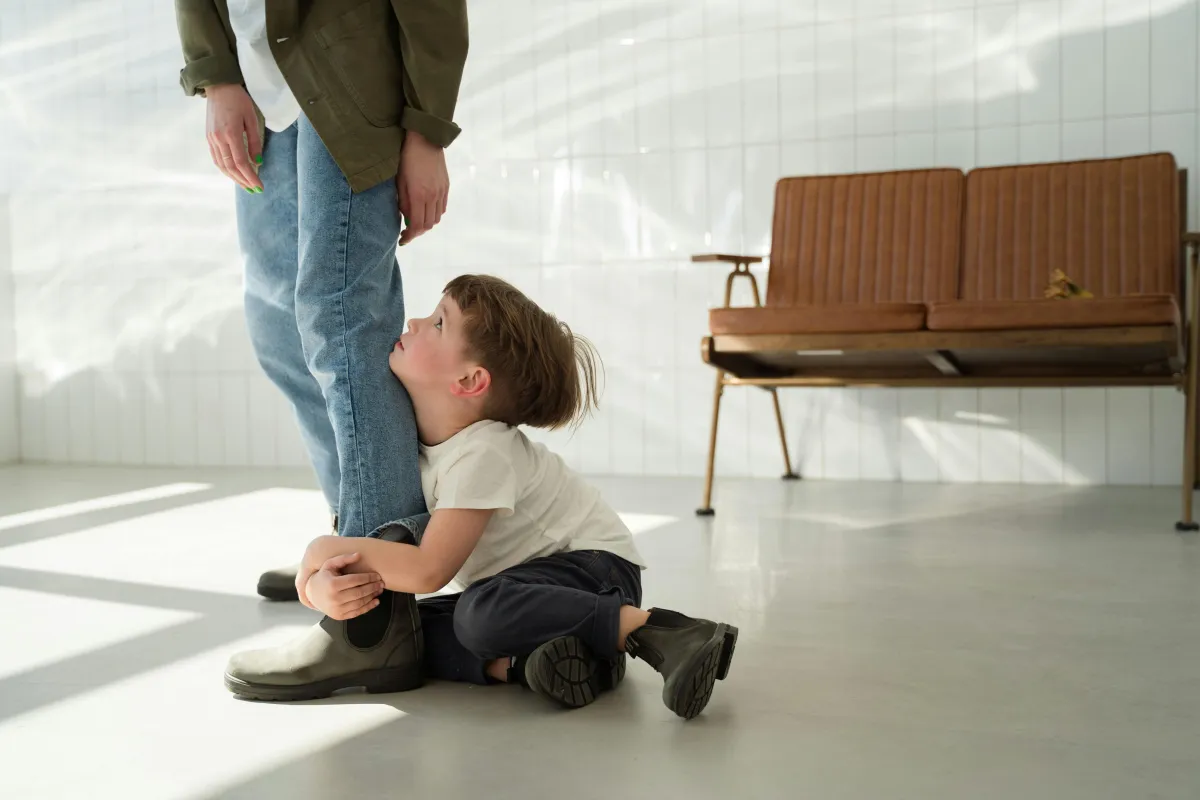 Child hanging from a parents leg