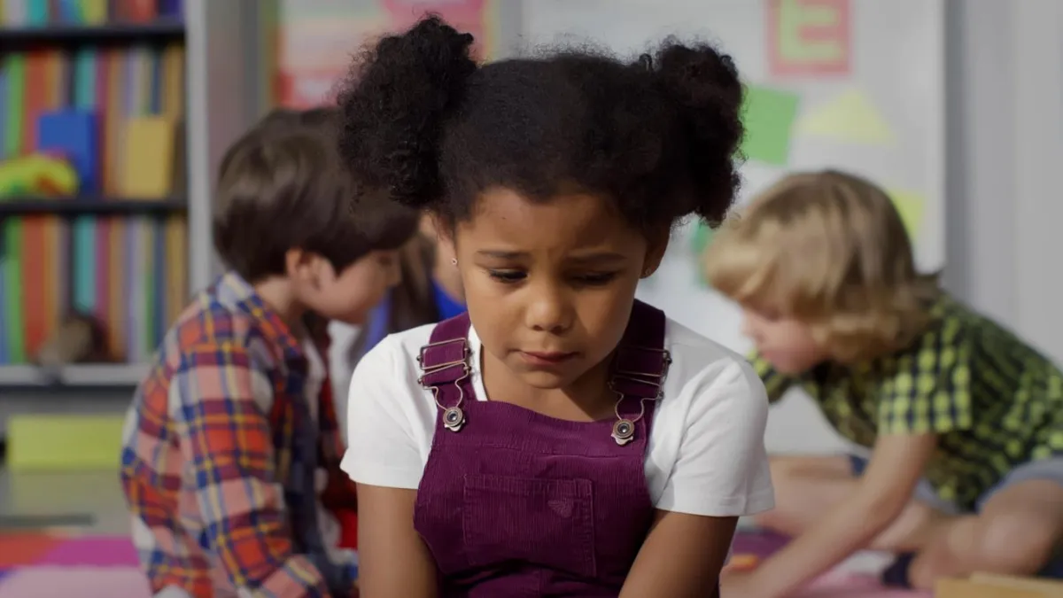 Girl sitting on the floor with a sad look on her face