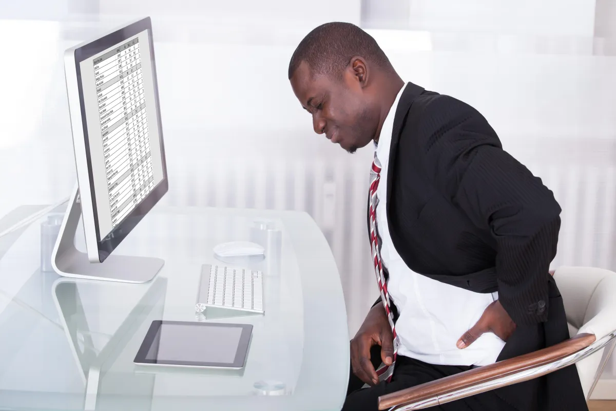 man with back pain sitting at computer