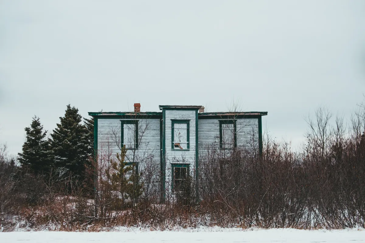 old, abandoned building resting on snowy ground