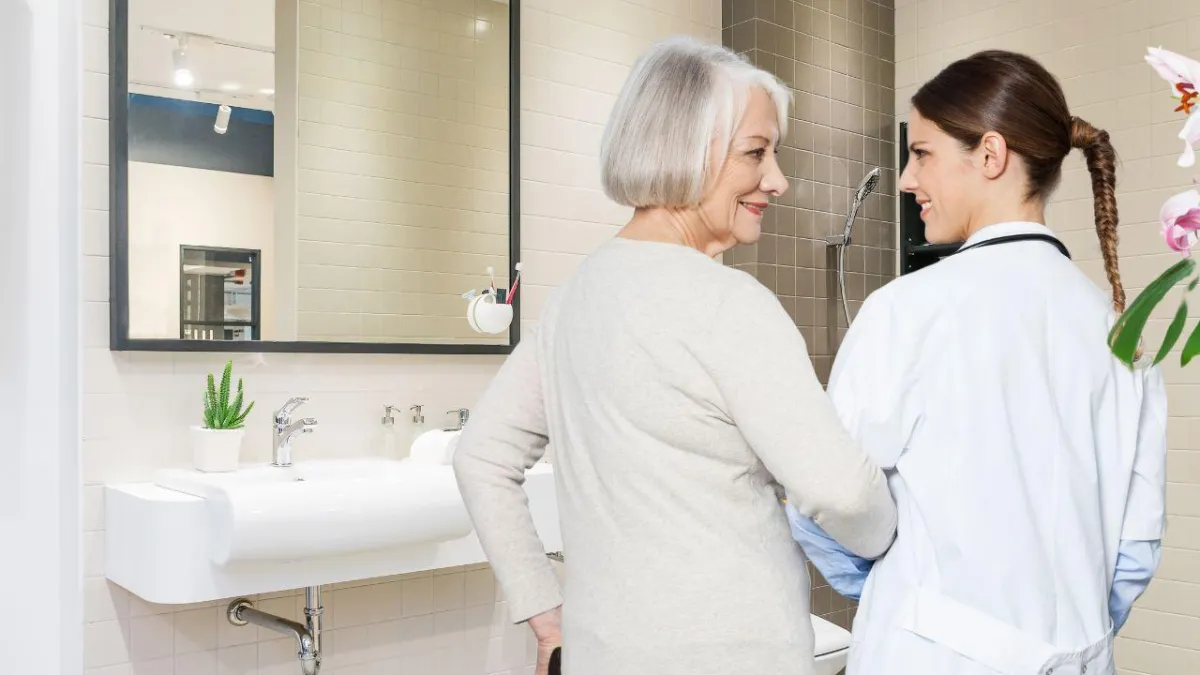 senior with her caregiver assisting in bathroom