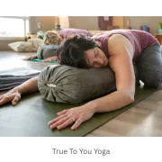 person in child's pose over a bolster