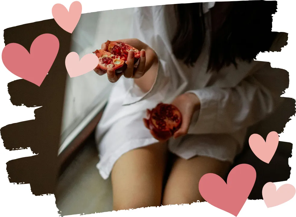 Woman sitting down holding a split pomegranate, symbolizing heavy bleeding and hormonal changes during perimenopause.