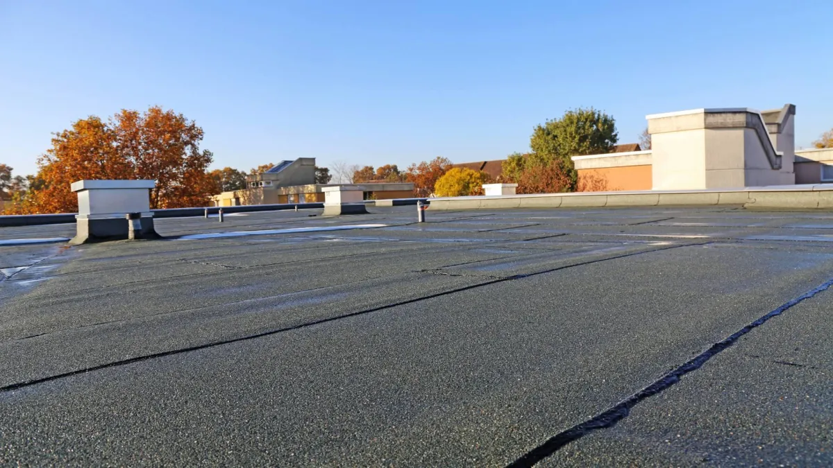 A gray commercial flat roof is displayed against a blue sky.