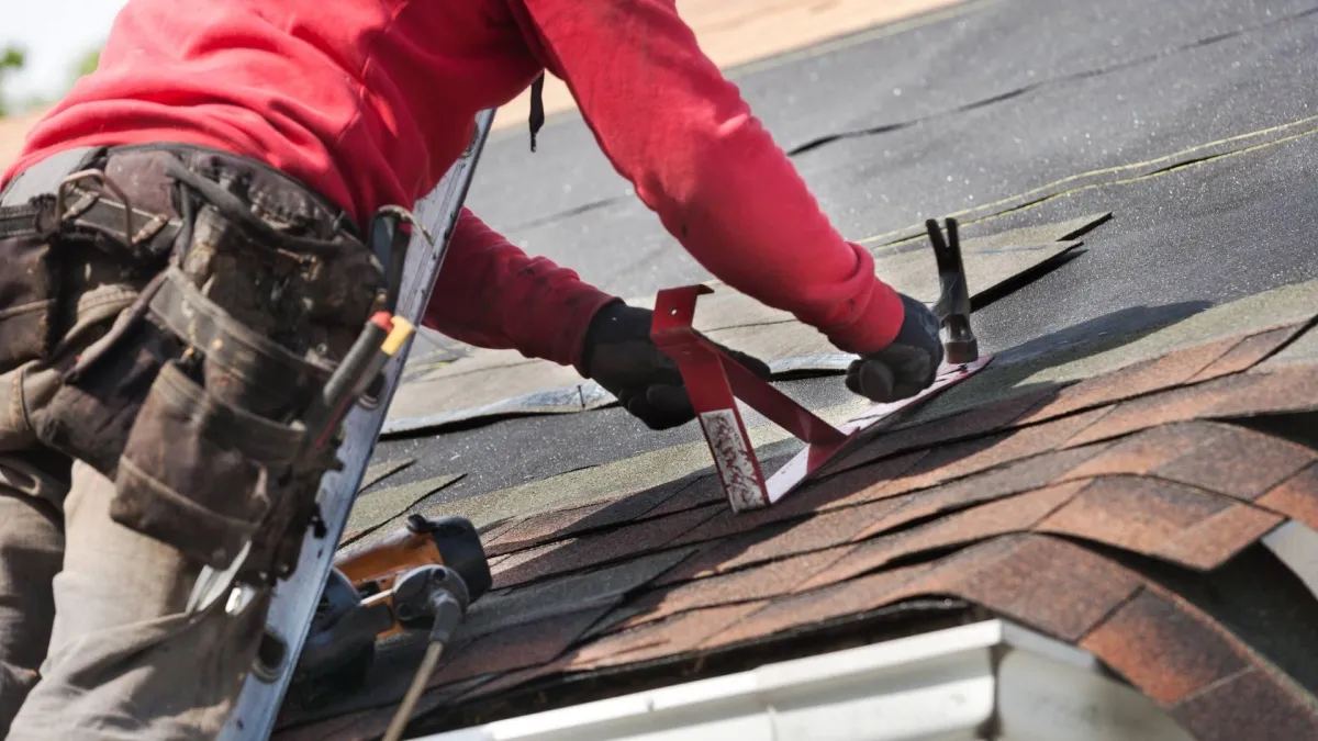 A contractor wears a red shirt and works on roof repair in Central Florida.