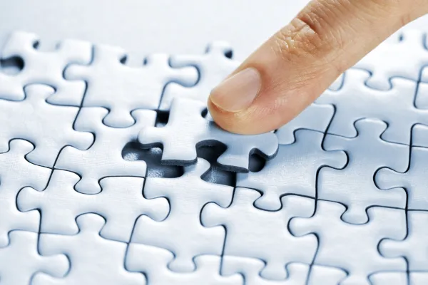 Close-up of hands placing the final puzzle piece