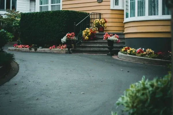 Smooth asphalt driveway with colorful flower decorations at front entry