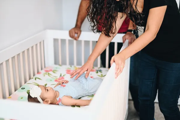 Mother gently putting baby to sleep in a cozy bedroom
