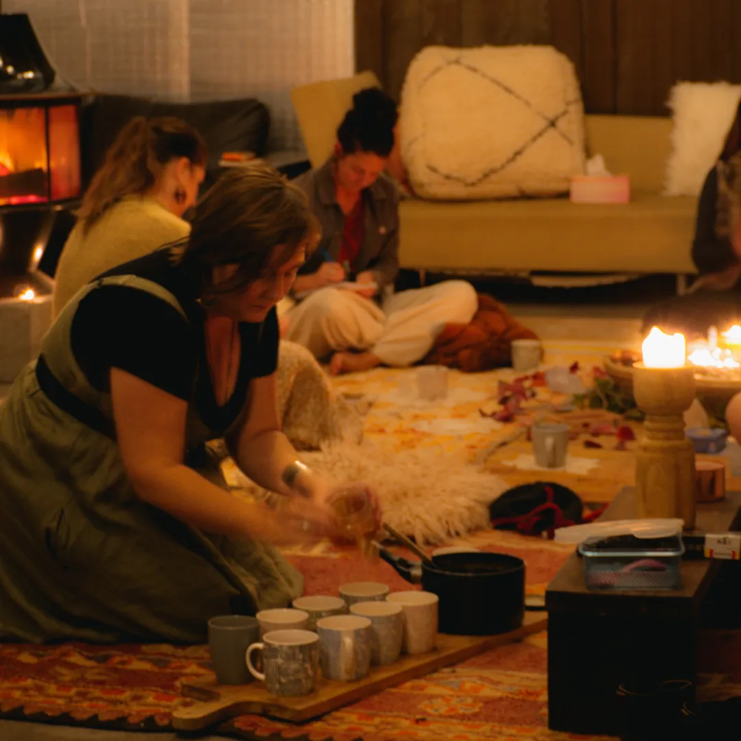 3 women in firelight pouring ceremonial chai