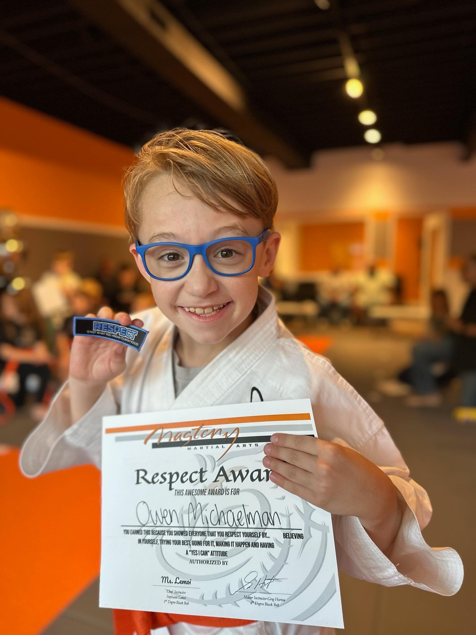 Smiling child holding a Respect Award certificate at Mastery Martial Arts, celebrating confidence, character development, and positive behavior