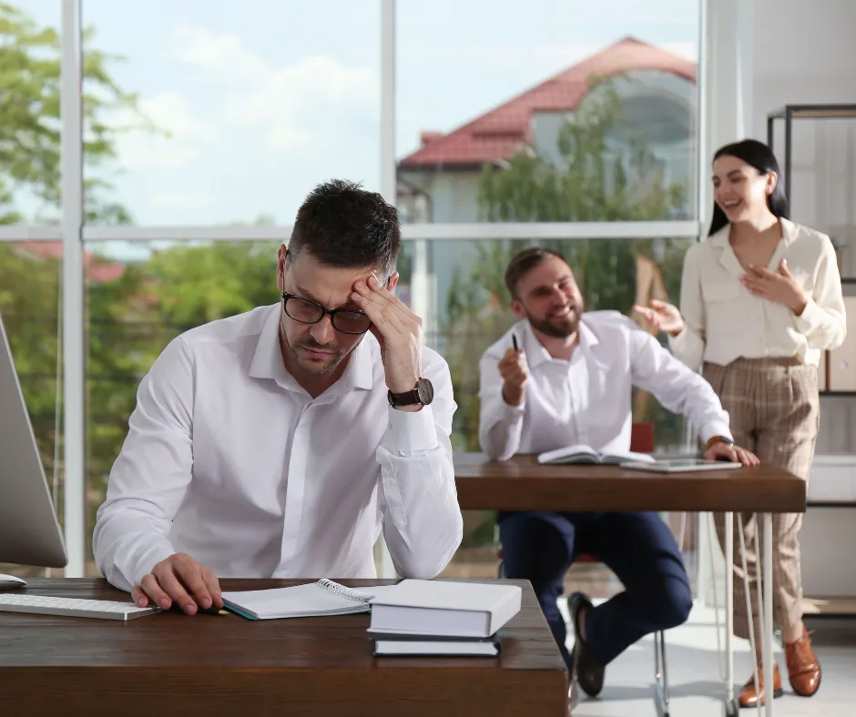 man sitting at desk being laughed at